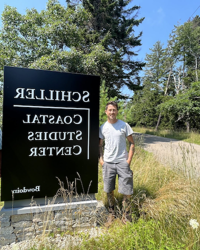 Joe Tourelotte standing next to Schiller Coastal Studies Center sign